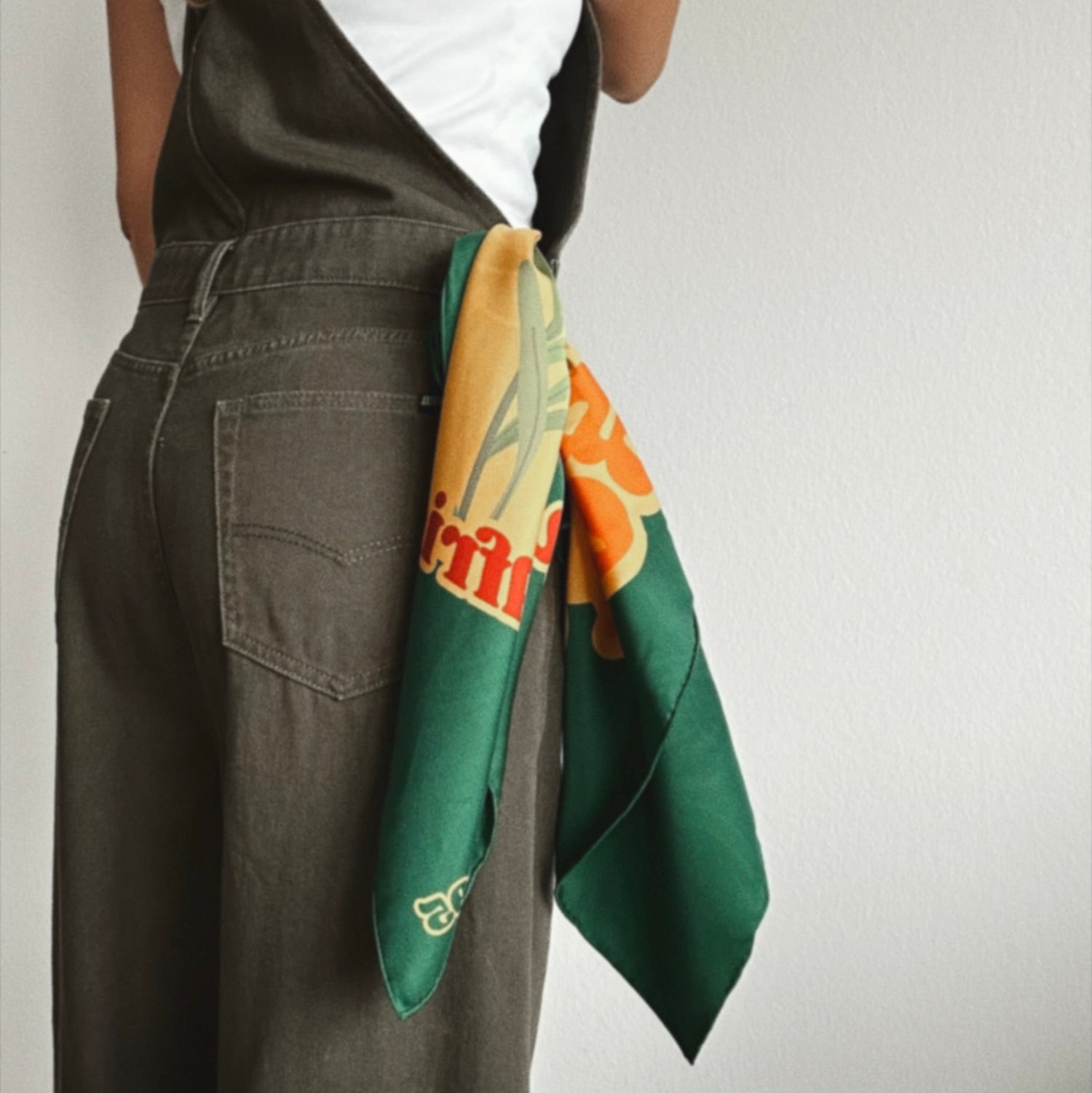 Green silk scarf from 1995 with orange and cream botanical print, tied around the waistband of khaki wide-leg dungarees